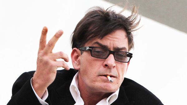 Charlie Sheen talks to the press and waves a sword from the top of a building after finding out he has been fired.